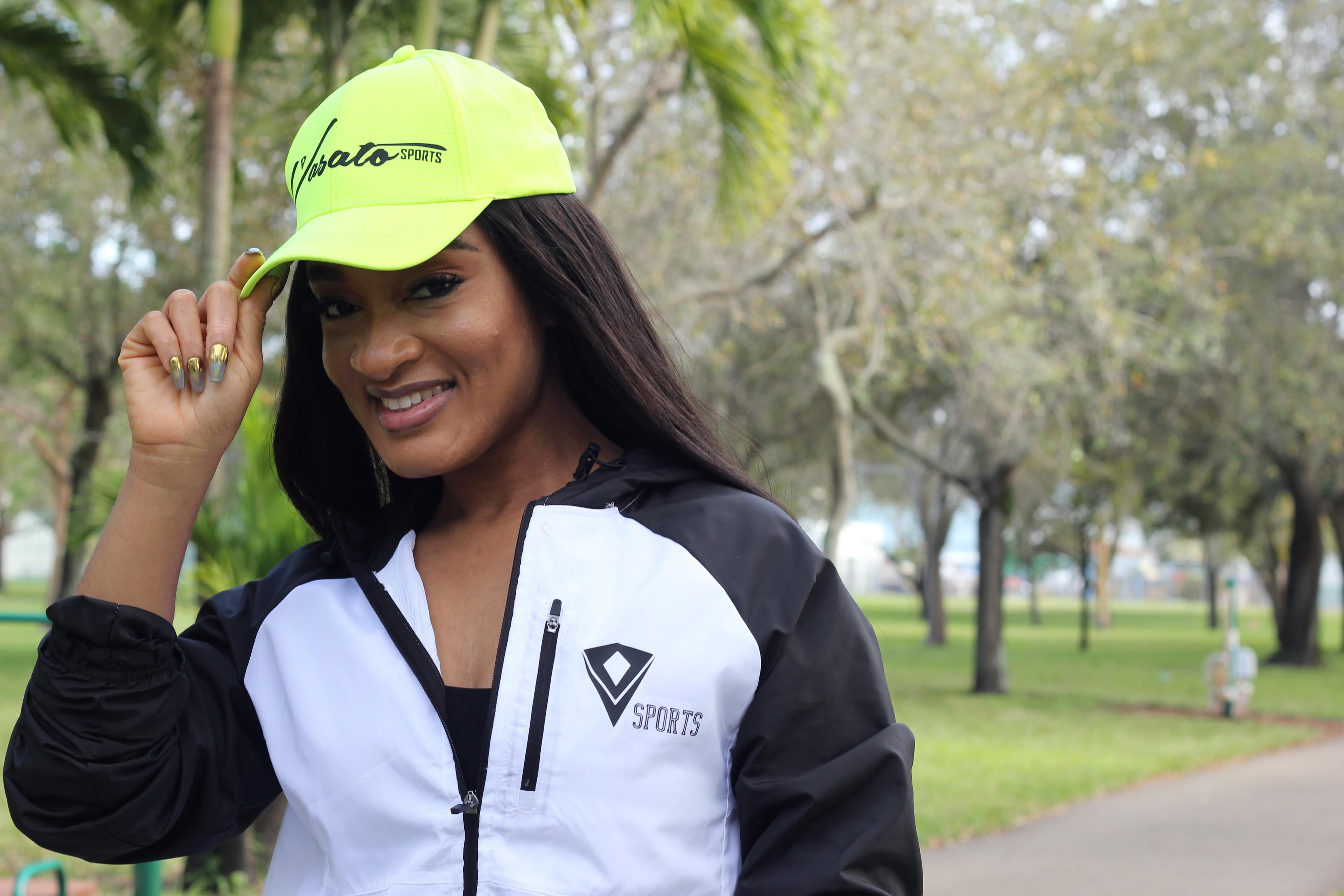 Model wearing a neon Vasato Sports cap and black and white jacket outdoors